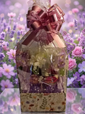 Garden in Bloom Floral Gift Basket in botanical wildflower box with purple crinkle paper, dried florals, sweet treats and butterfly accents wrapped in polka dot cellophane with rose gold pull bow surrounded by lavender and roses